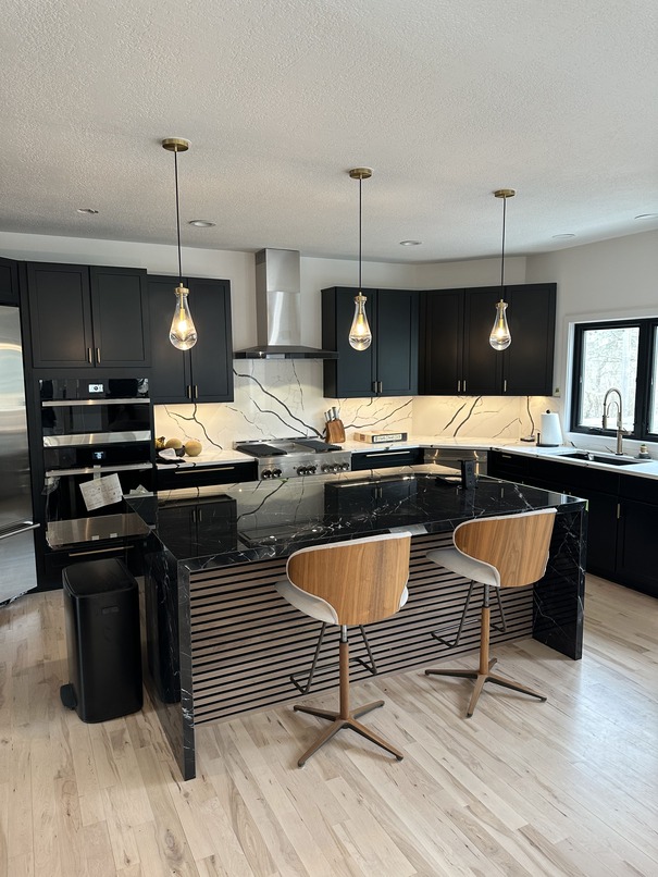 Modern kitchen interior painted by Adel Painting Company Phillips Pro Painting featuring black cabinets, marble backsplash, and wooden accents.
